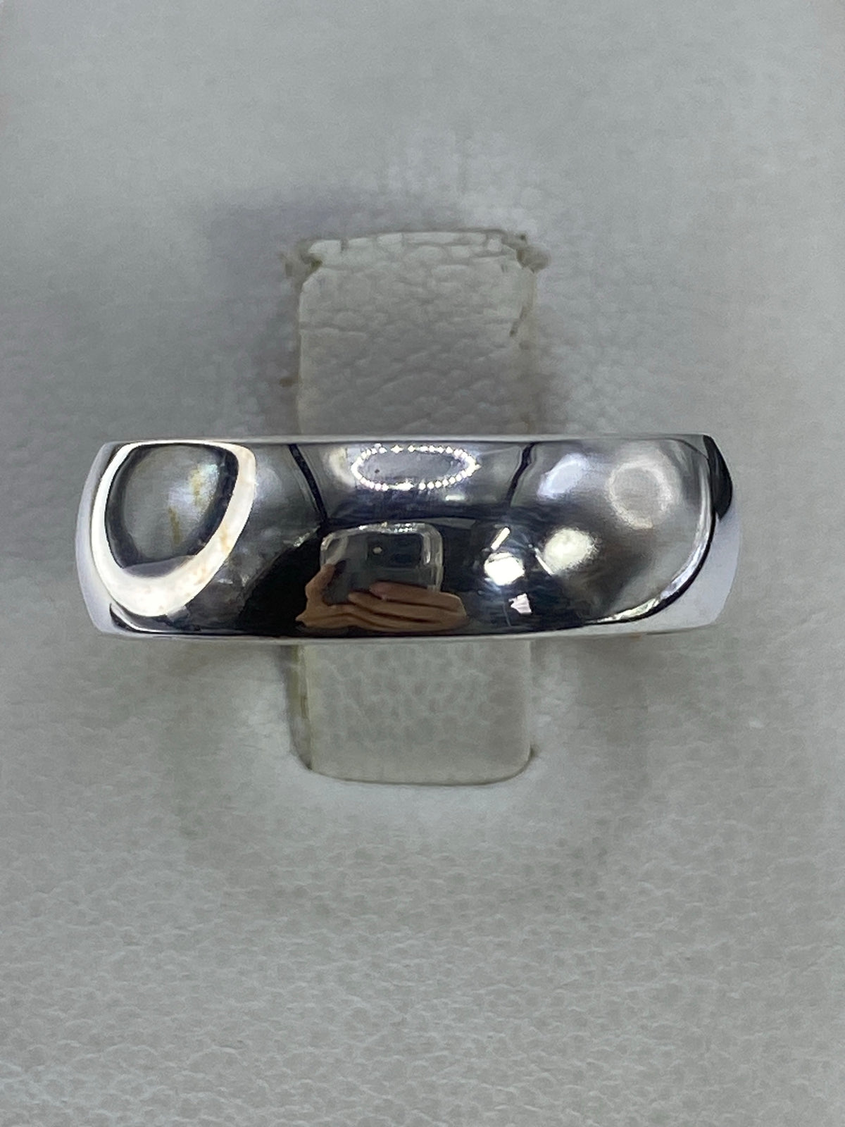Anillo de plata 925 banda pulida minimalista en la mano de un hombre, mostrando el brillo del acabado