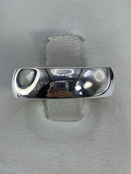 Anillo de plata 925 banda pulida minimalista en la mano de un hombre, mostrando el brillo del acabado