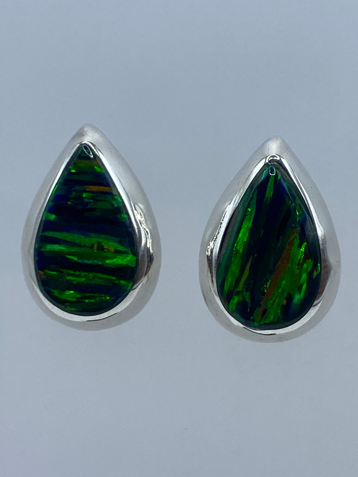 Aretes de plata con opalo de fuego verde en forma de gota, par completo sobre fondo gris