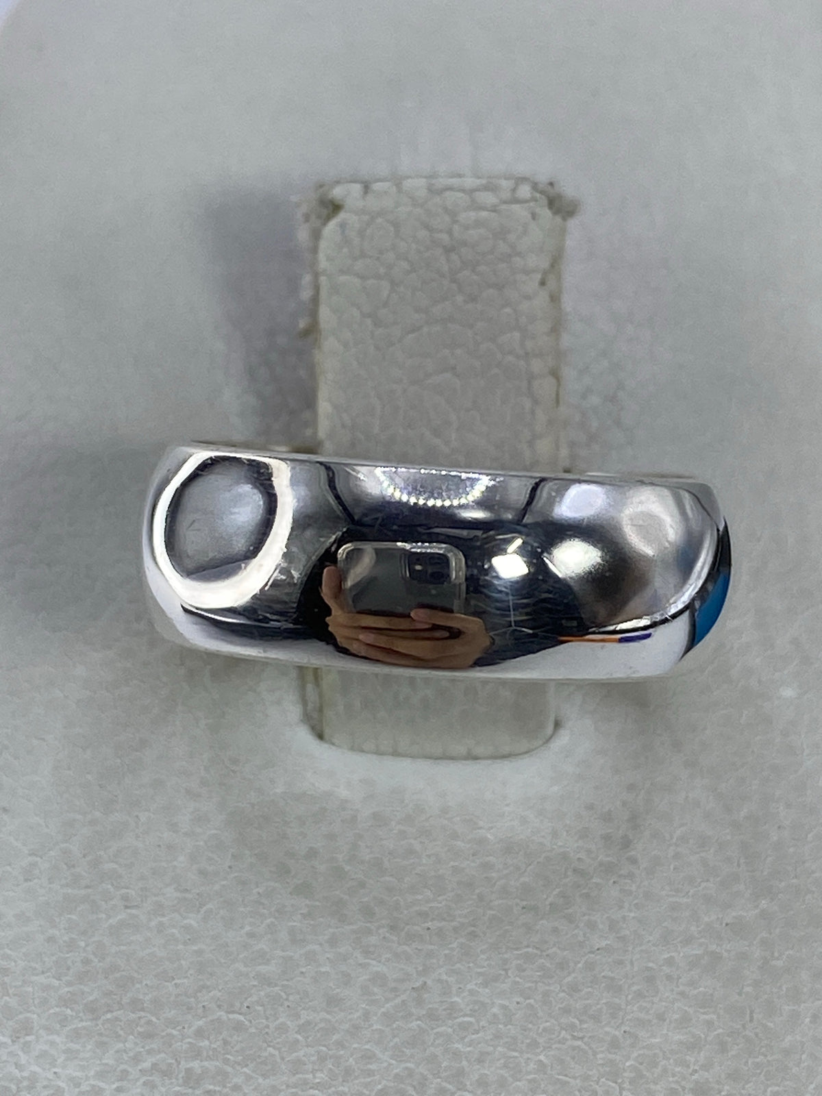 Anillo de plata 925 pulido, banda minimalista, en la mano sobre fondo blanco