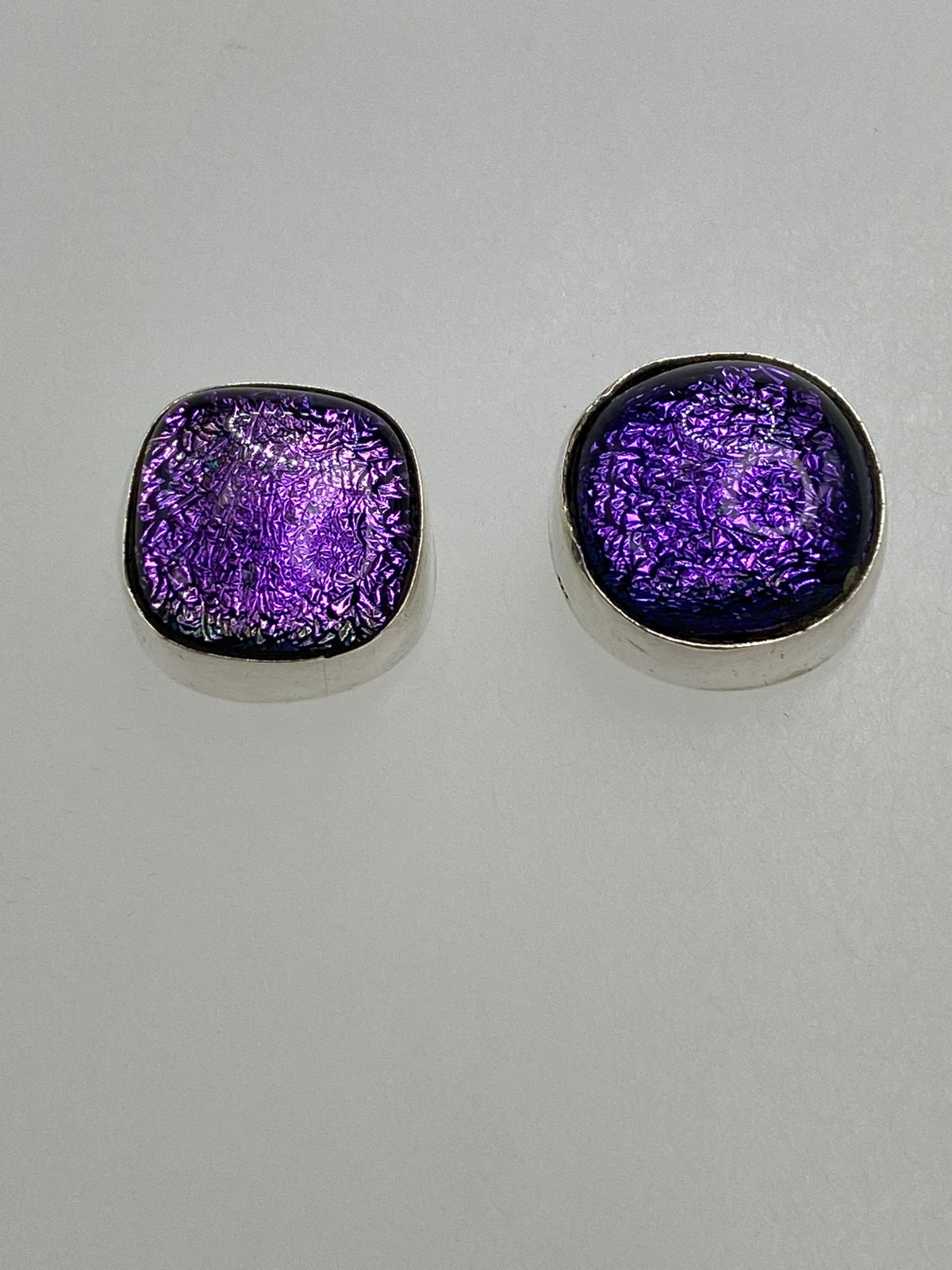 Aretes de plata con piedra morada brilla a la luz, vista detallada de engaste