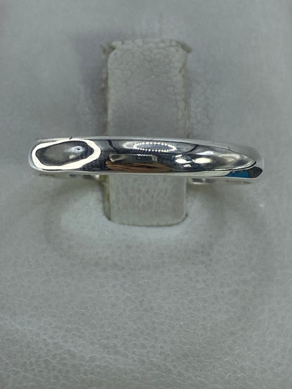 Anillo de plata 925 pulido en forma de banda lisa en la mano de una mujer