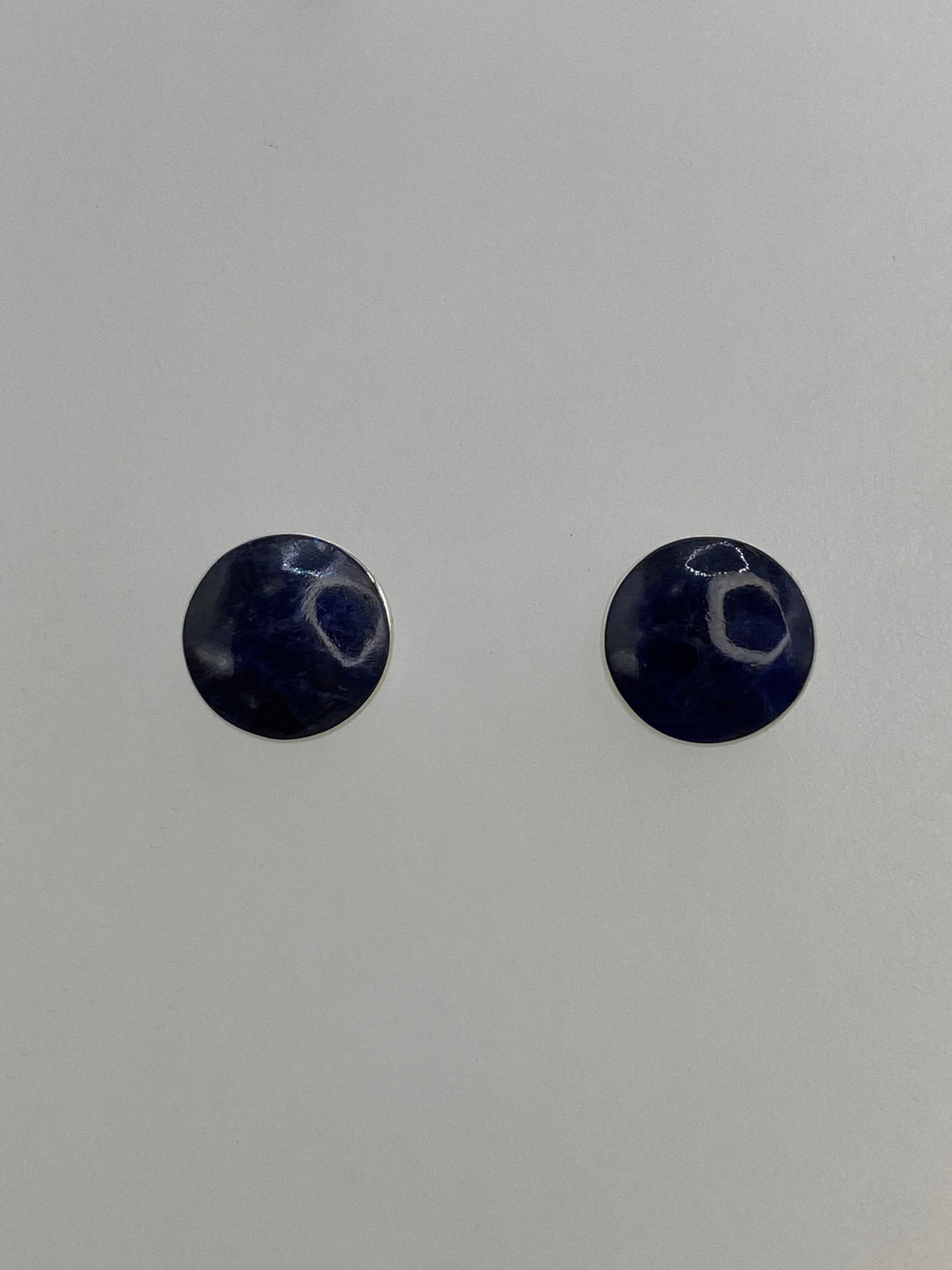 Par de aretes de plata con lapislázuli morada, pequeños y delicados, sobre fondo blanco