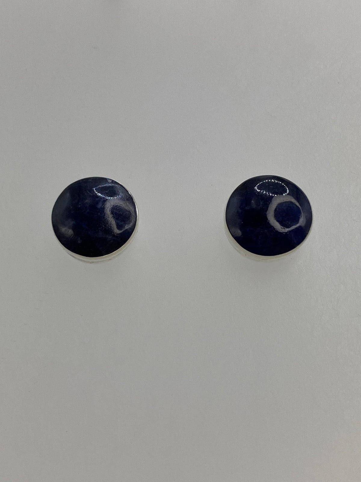 Detalle de un arete mostrando la piedra lapislázuli morada engastada en plata 950