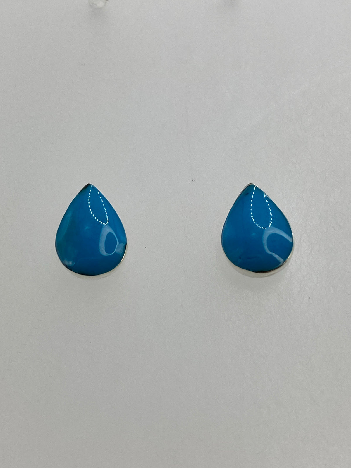 Detalle de los aretes mostrando el engaste de coral a mano en plata 950