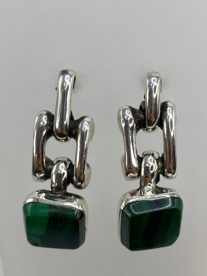 Arete de malaquita mostrando las vetas verde profundo y el marco escultórico de plata