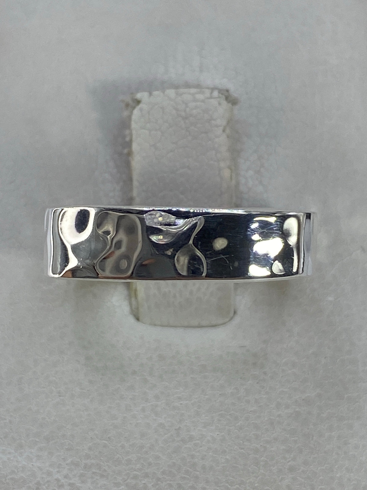 Anillo de plata cuadrado minimalista en la mano, vista frontal del diseño geométrico