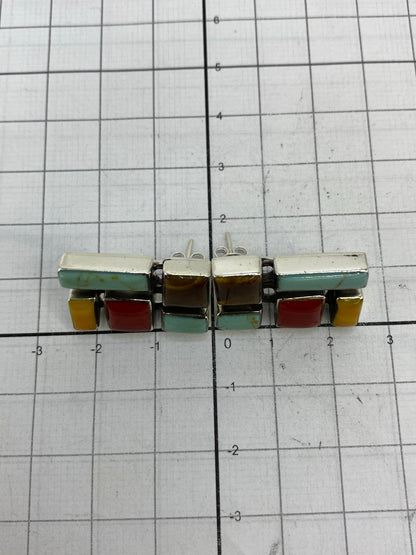 Aretes en la mano mostrando tamaño de 2.4 cm de largo y la combinación de colores