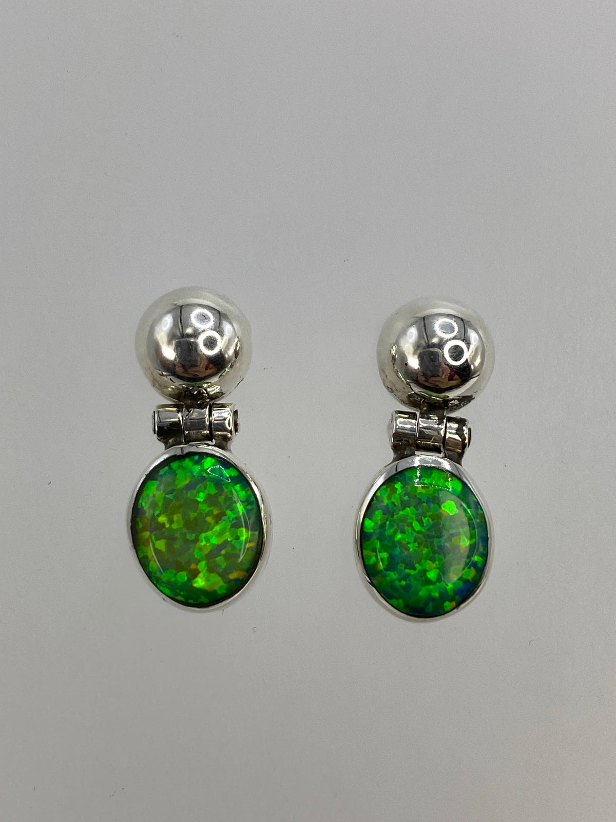 Par de aretes de plata 950 con ópalo de fuego verde limón, vista frontal sobre fondo blanco