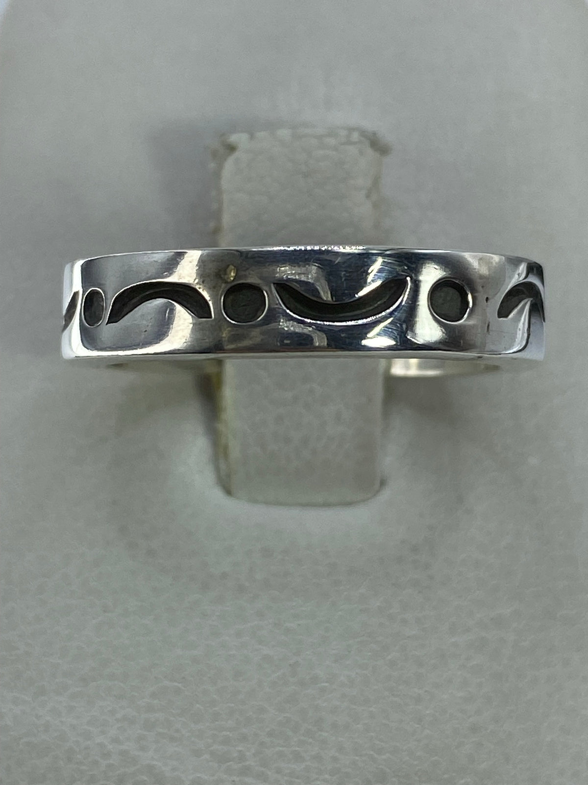 Anillo de plata 925 minimalista con detalle de curvas y círculos, visto desde arriba sobre fondo gris