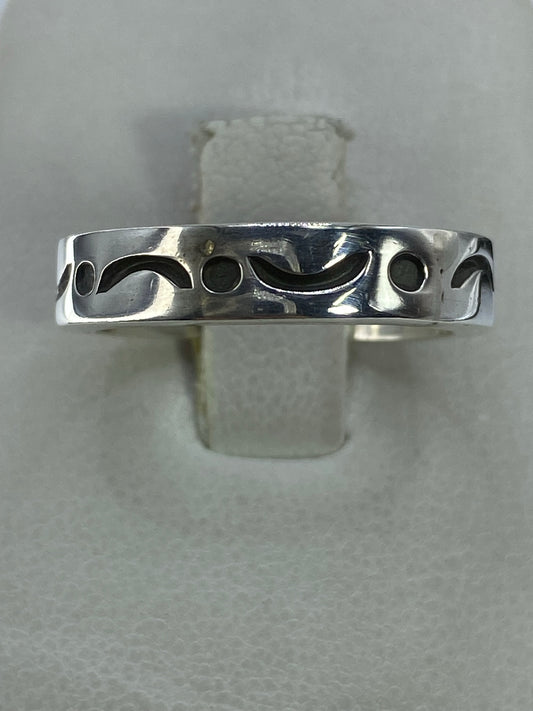 Anillo de plata 925 minimalista con detalle de curvas y círculos, visto desde arriba sobre fondo gris