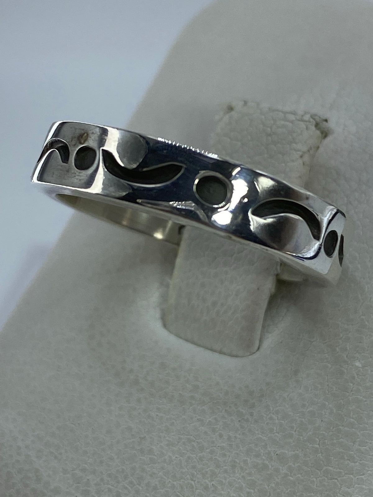 Anillo de plata sin piedras con patrón de relieve, vista lateral mostrando el pulido brillante