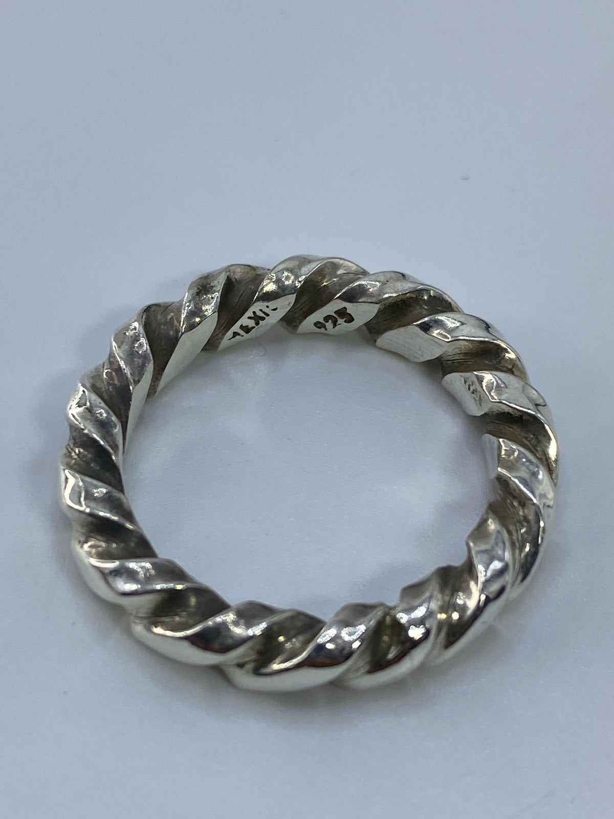 Anillo sobre fondo blanco con iluminación que resalta el acabado pulido