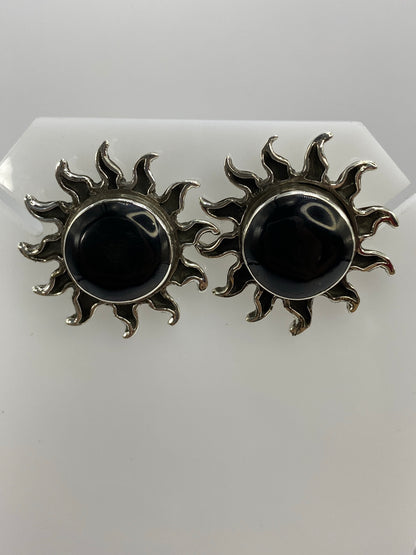 Aretes de plata en forma de sol con ónix negro engastado en el centro, vista frontal