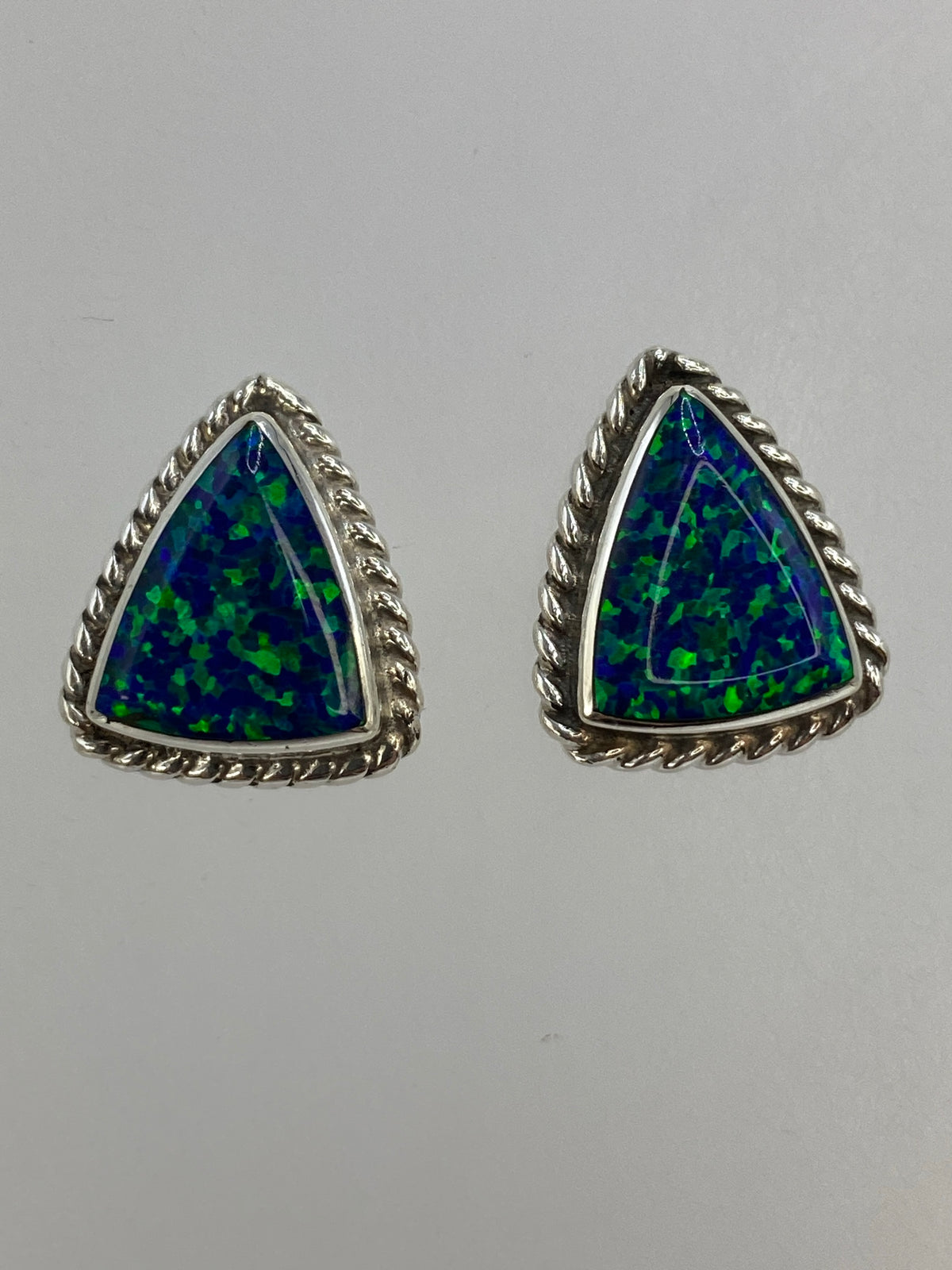Par de aretes triangulares de plata 950 con ópalo de fuego azul sobre fondo blanco