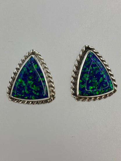 Aretes en la mano mostrando el tamaño compacto y el brillo del ópalo