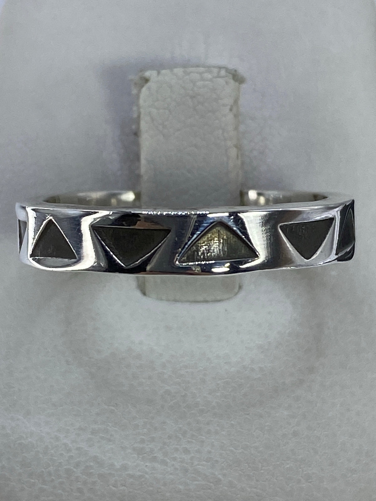 Anillo de plata con triángulos geométricos calados en la mano de una persona