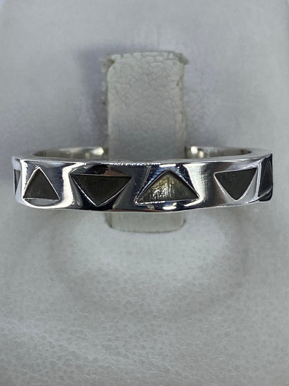 Anillo de plata con triángulos geométricos calados en la mano de una persona