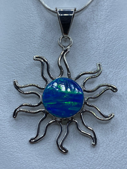 Dije de plata con ópalo de fuego azul en forma de sol sobre cadena plateada
