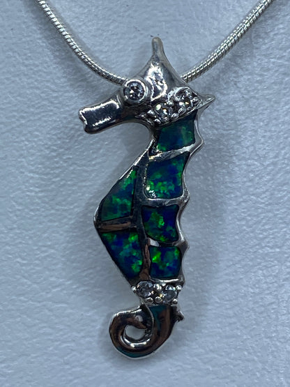 Vista frontal del dije mostrando los segmentos de ópalo azul incrustados en la forma del caballito