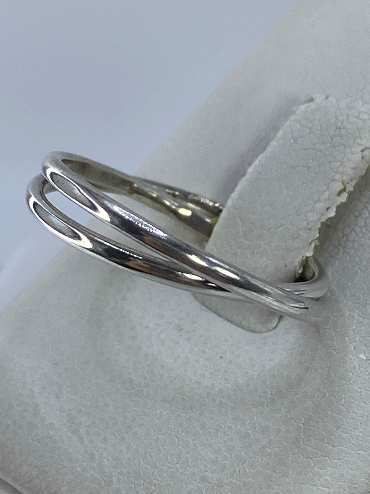 Anillo minimalista de dos bandas en mano, mostrando el pulido espejo