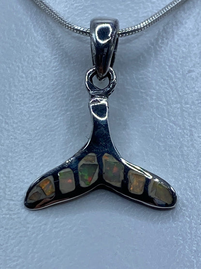 Dije de plata en forma de cola de ballena con ópalo de fuego tornasol colgando de una cadena de plata serpentina