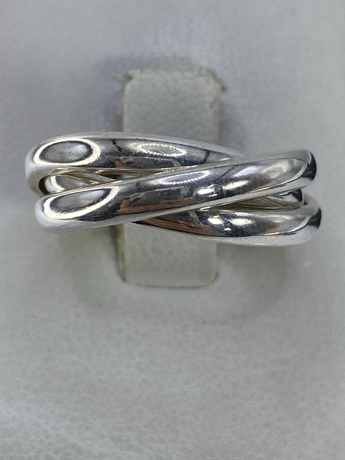 Anillo de plata con tres bandas entrelazadas en pulido espejo sobre fondo blanco