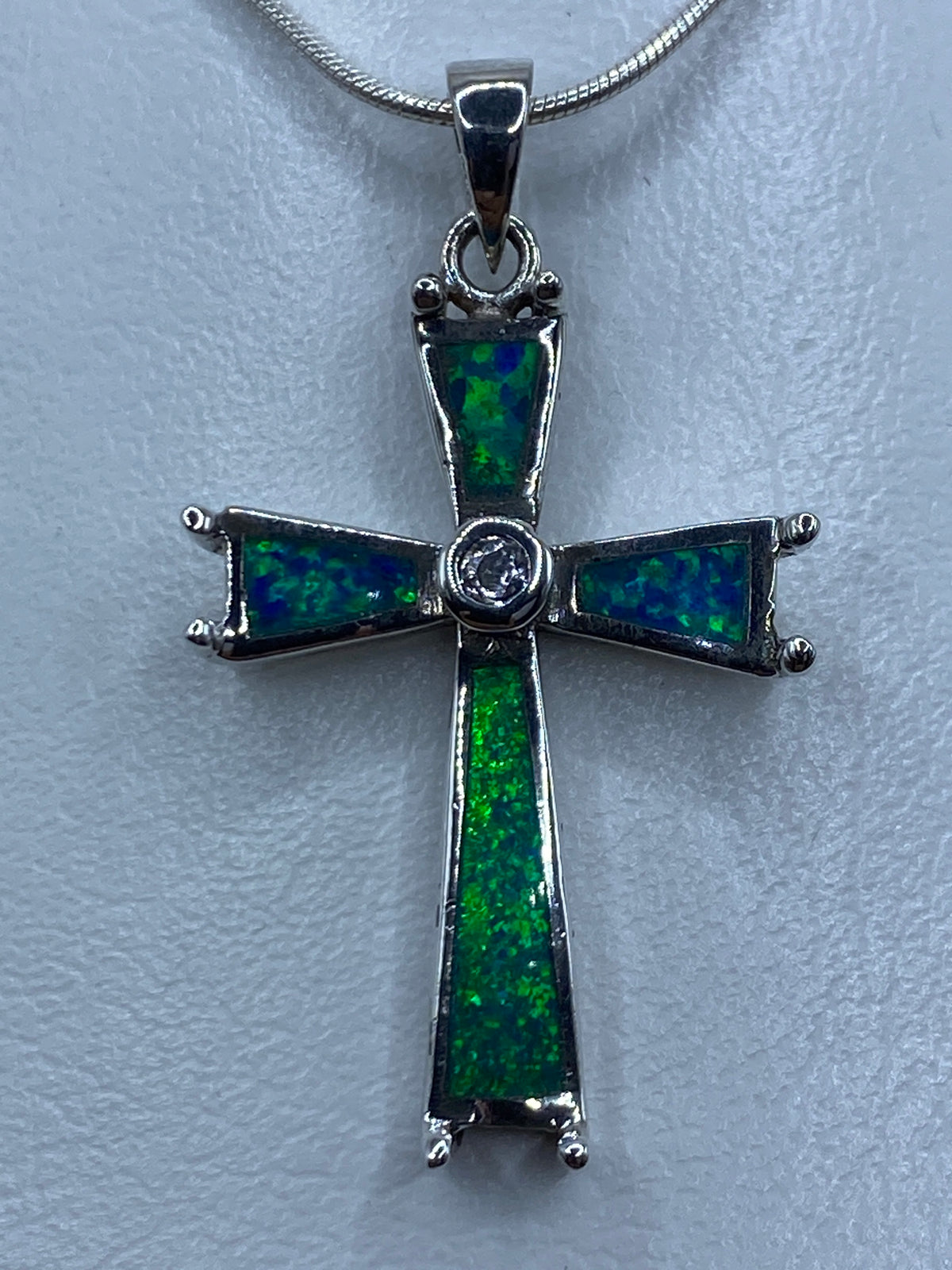 Dije cruz de plata 925 con ópalo de fuego azul colgado de cadena plateada