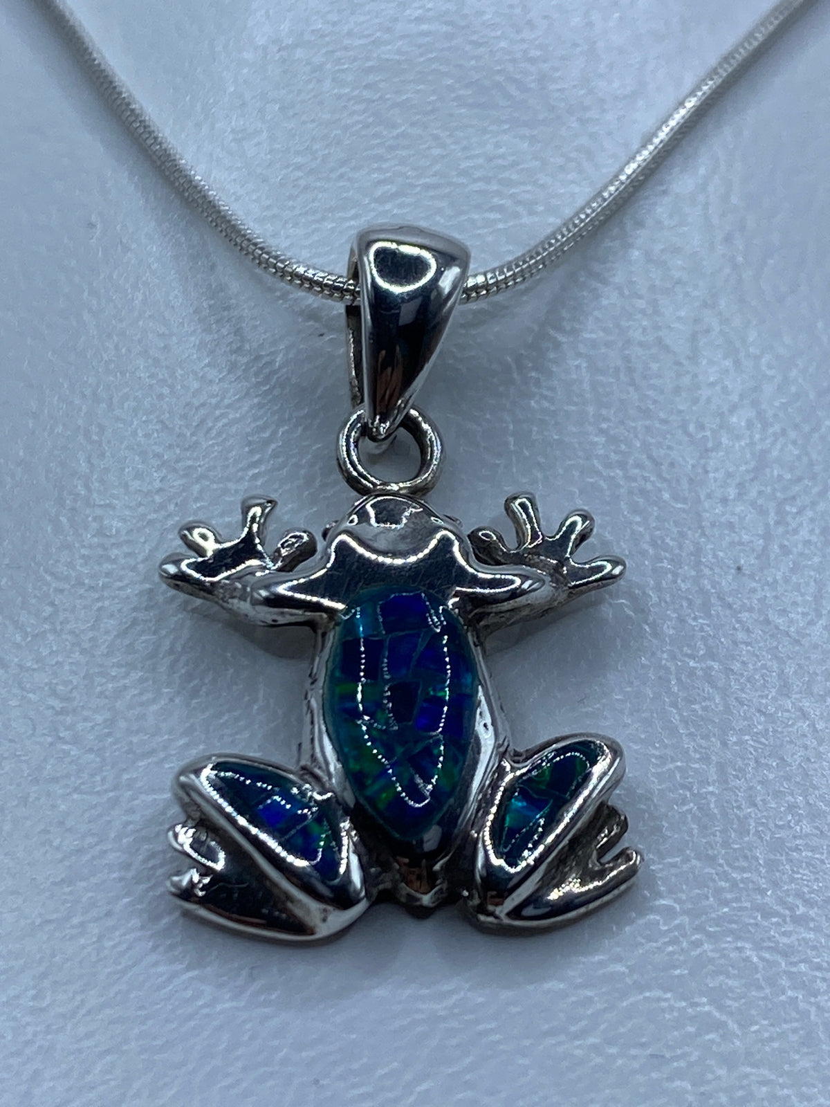 Detalle del ópalo de fuego azul incrustado en el cuerpo de la rana de plata