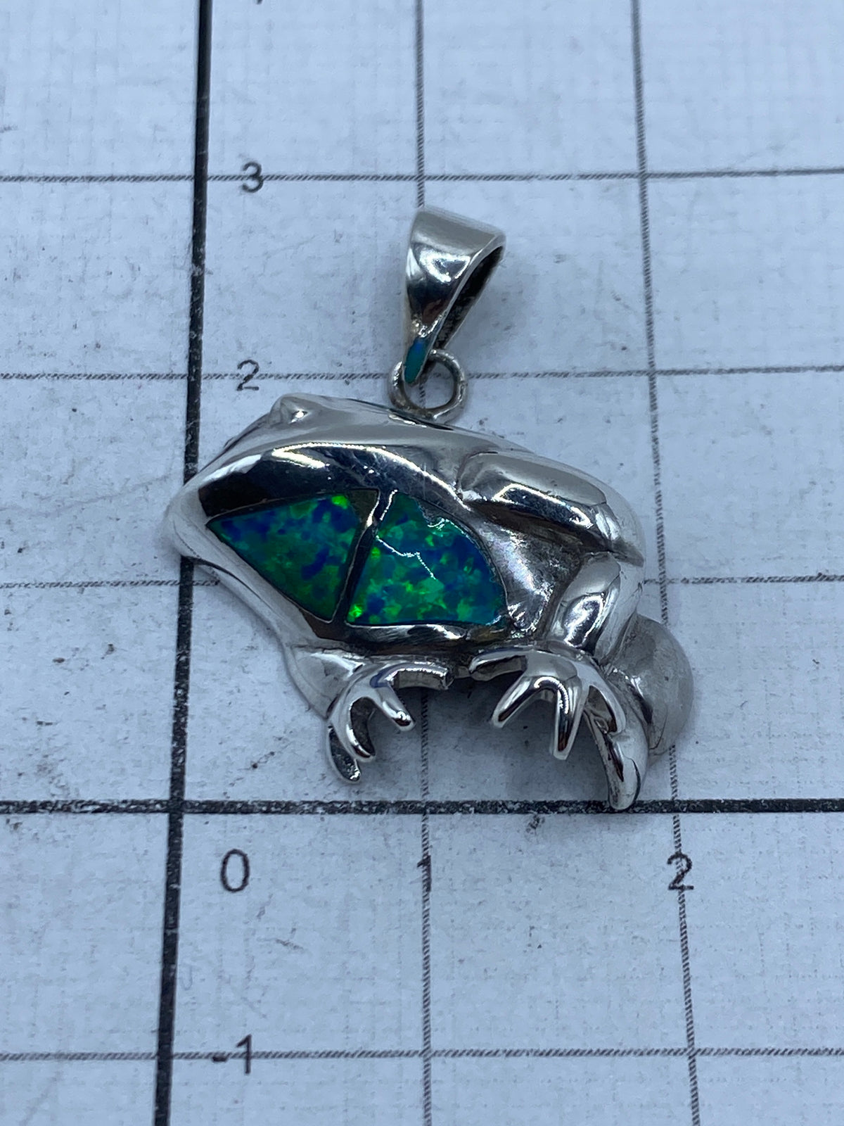 Dije sapo de plata sobre escala de centímetros — 2.8 cm de largo