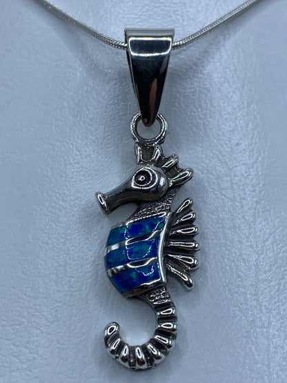 Dije caballito de mar en plata 950 con ópalo azul engastado, colgando en cadena de plata