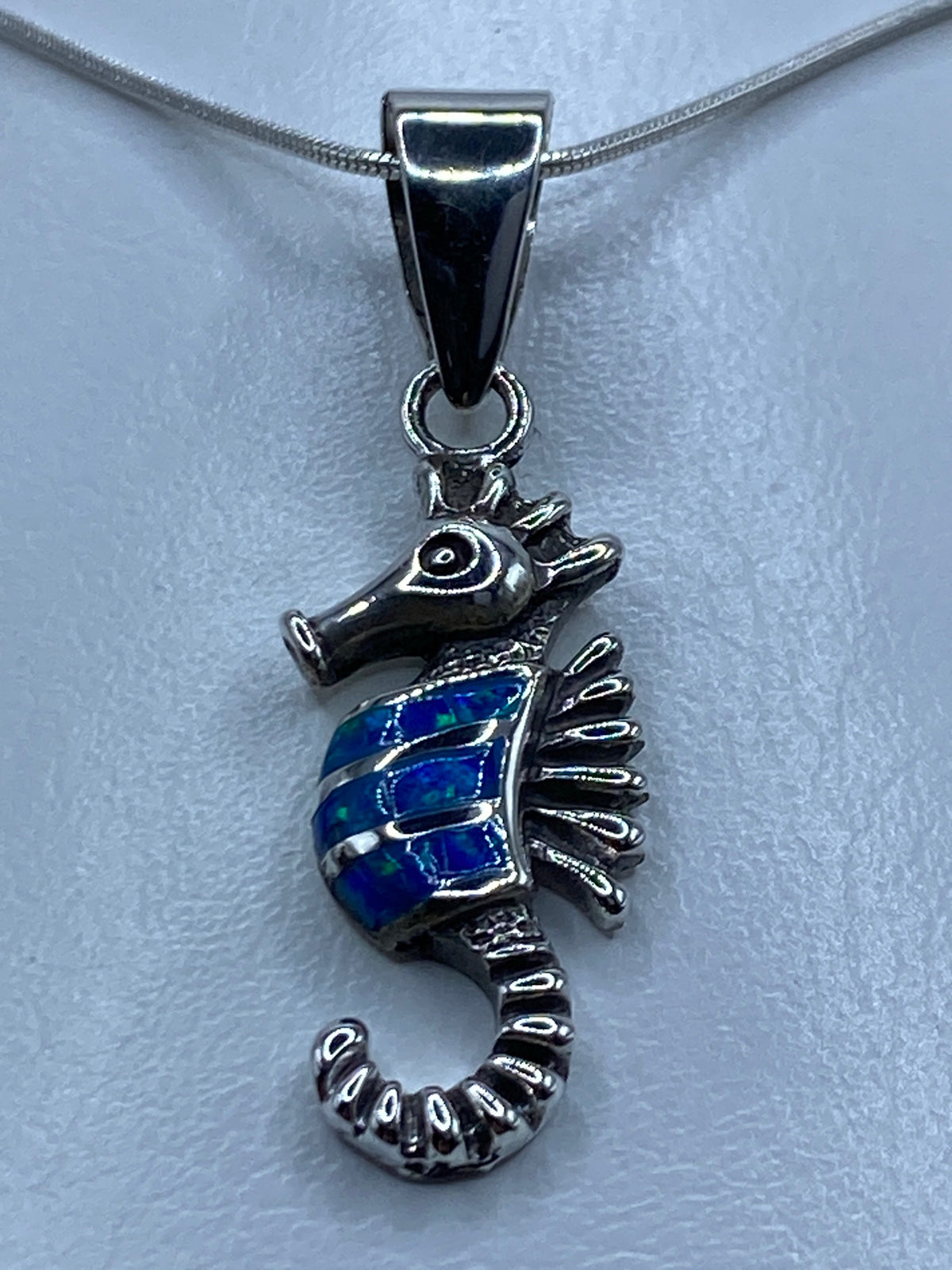 Detalle del ópalo de fuego azul en la cola del caballito de mar grabado a mano