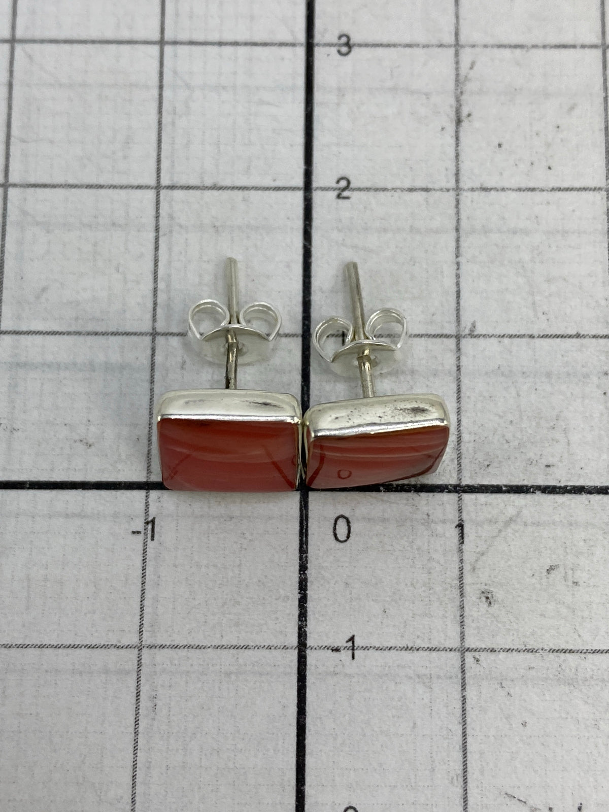 Aretes de plata con coral sobre fondo blanco, mostrando el Quinto 950