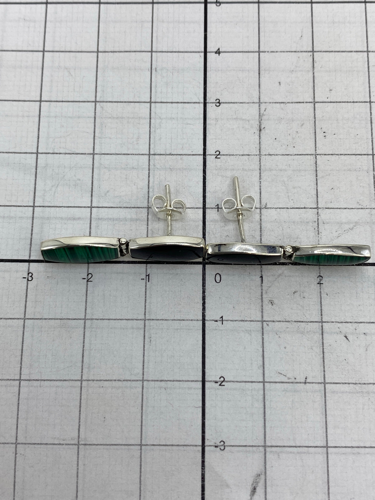 Aretes sobre regla de centímetros confirmando medidas de 2.7 cm de largo