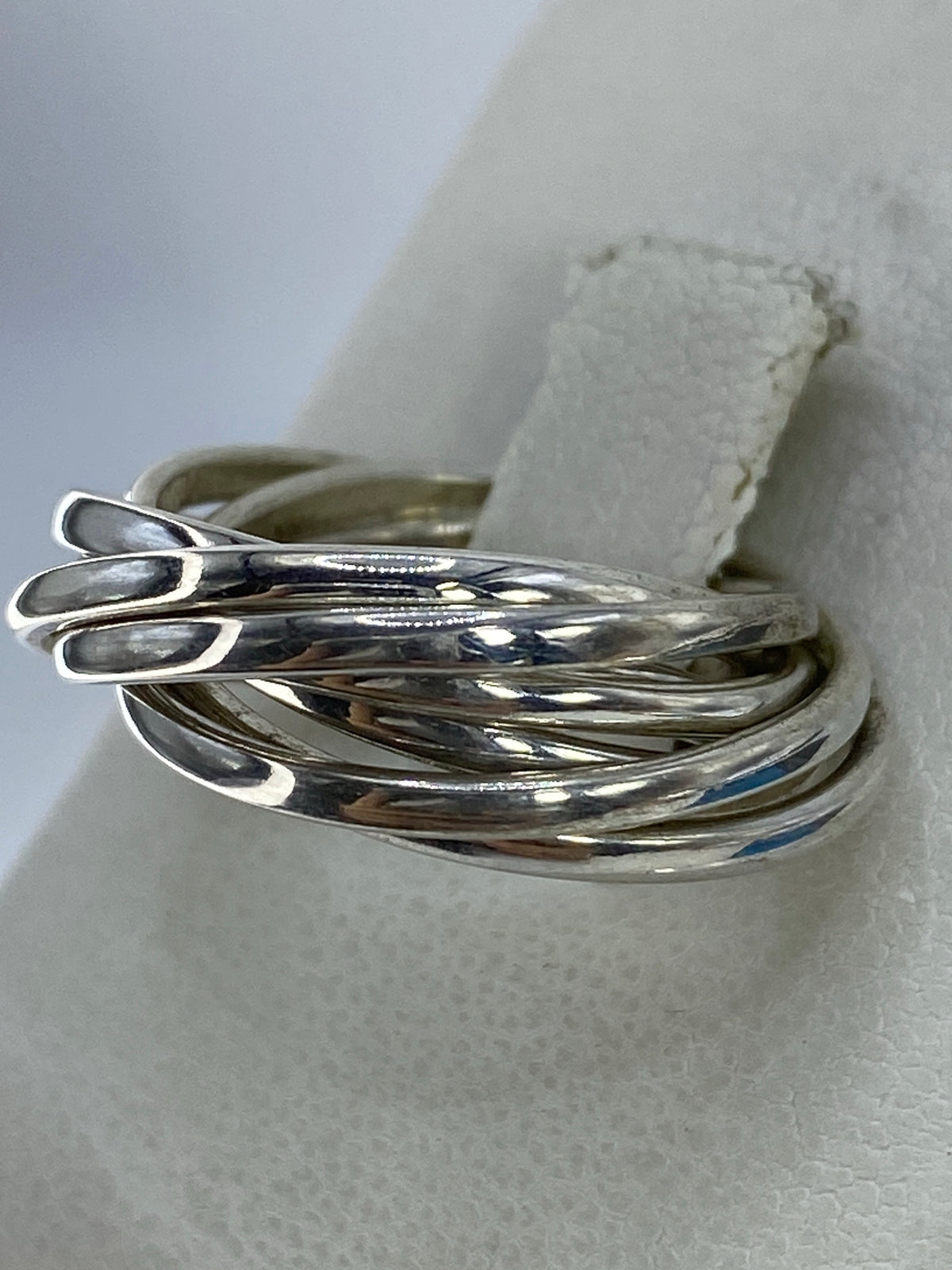 Anillo de plata entrecruzado en la mano, mostrando el brillo pulido