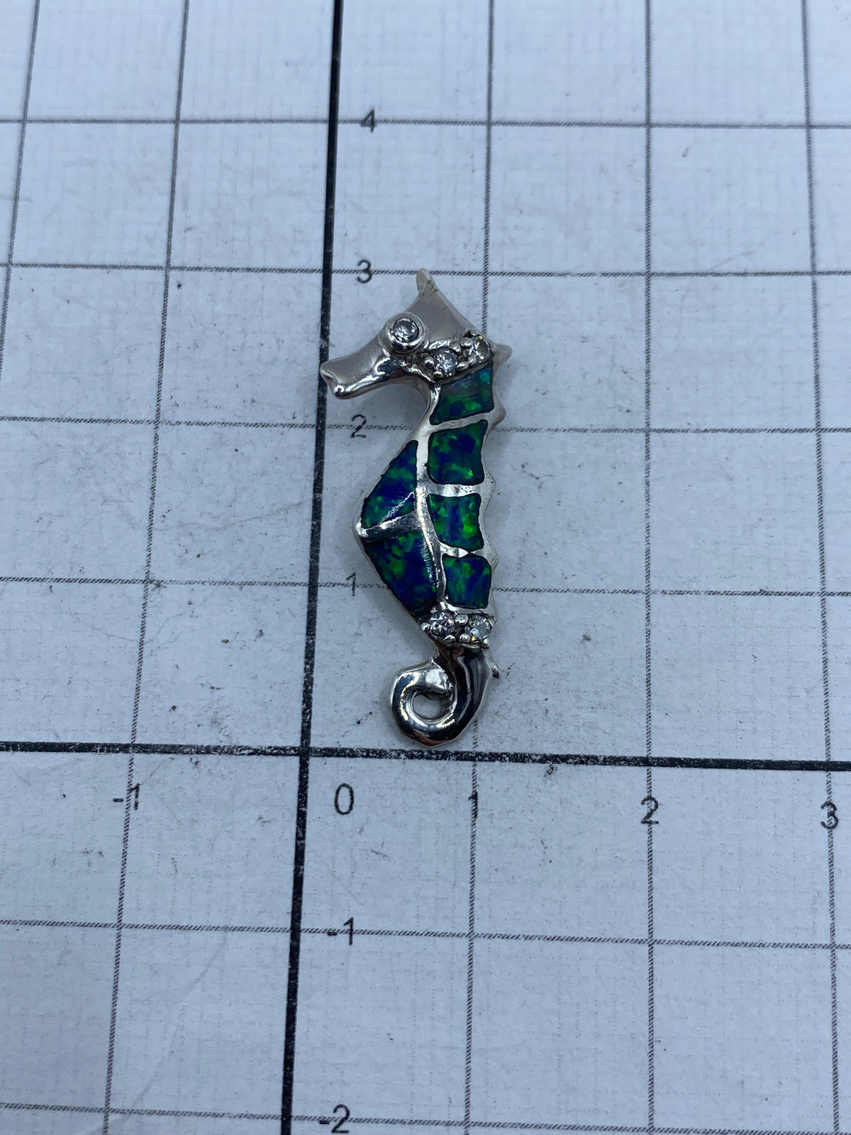Caballito de mar de plata sobre regla métrica mostrando tamaño real de 3 cm