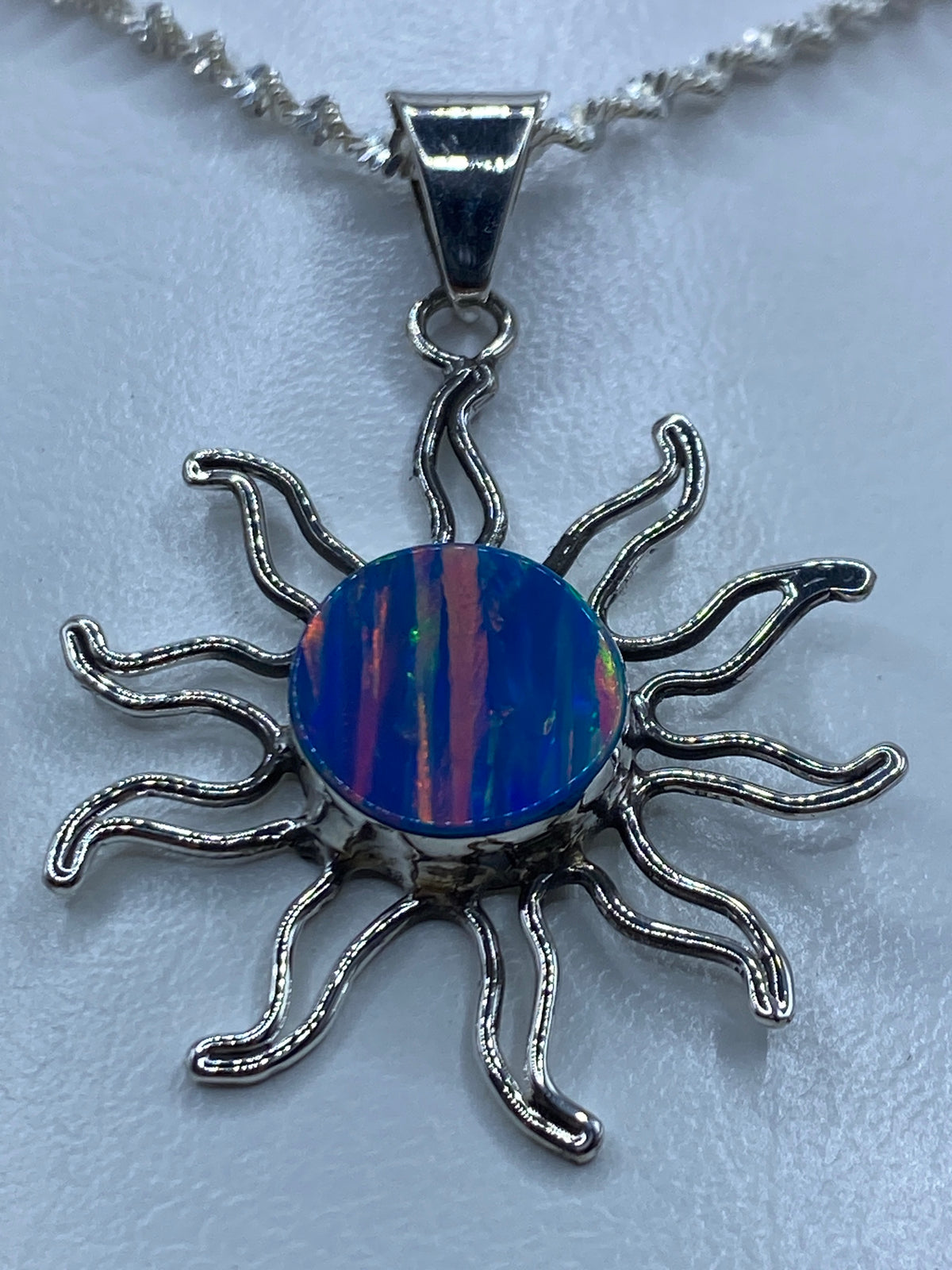 Detalle del ópalo de fuego azul dentro del dije solar de plata