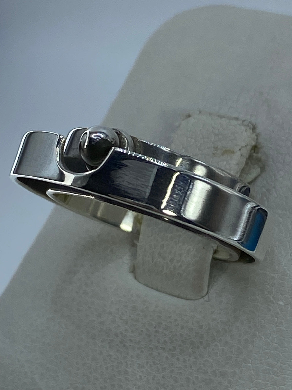 Anillo minimalista en plata pulida sobre dedo, mostrando el acabado espejo