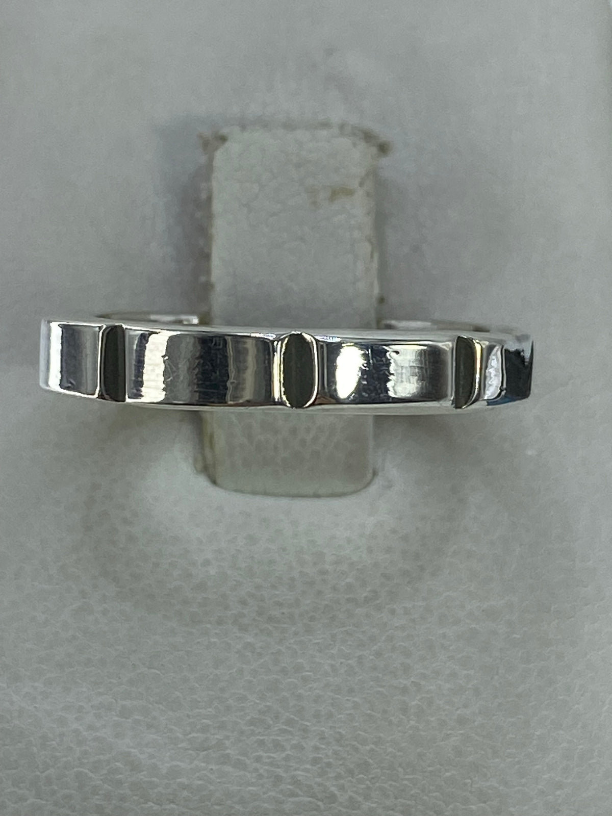 Anillo de plata 925 con diseño geométrico de franjas minimalista, visto desde arriba sobre fondo gris