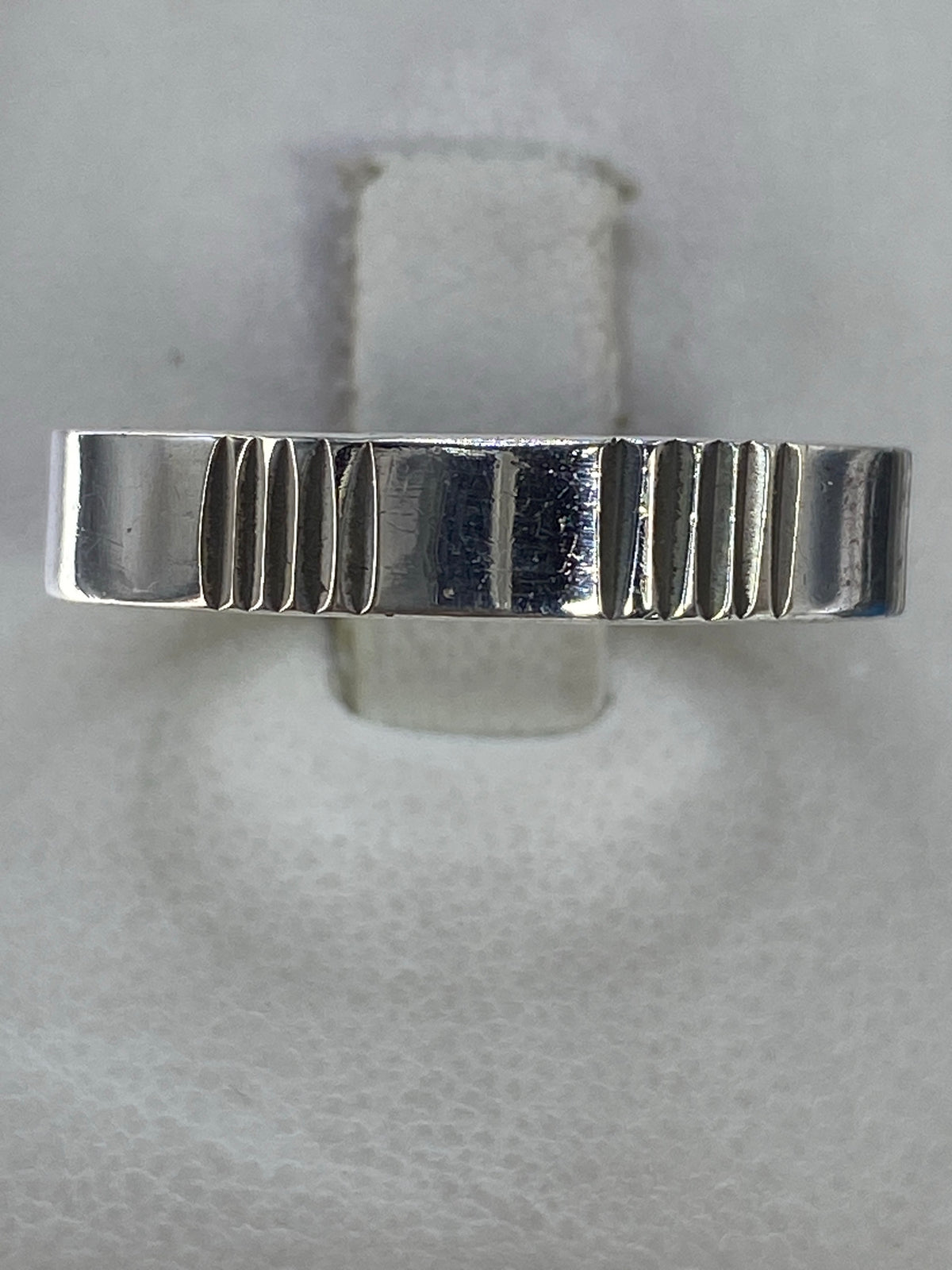 Anillo de plata 925 con líneas geométricas talladas, vista superior en estuche blanco