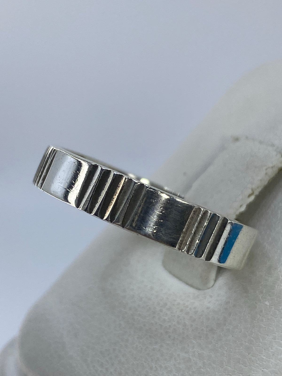 Detalle de las líneas geométricas del anillo de plata, mostrando el patrón tallado
