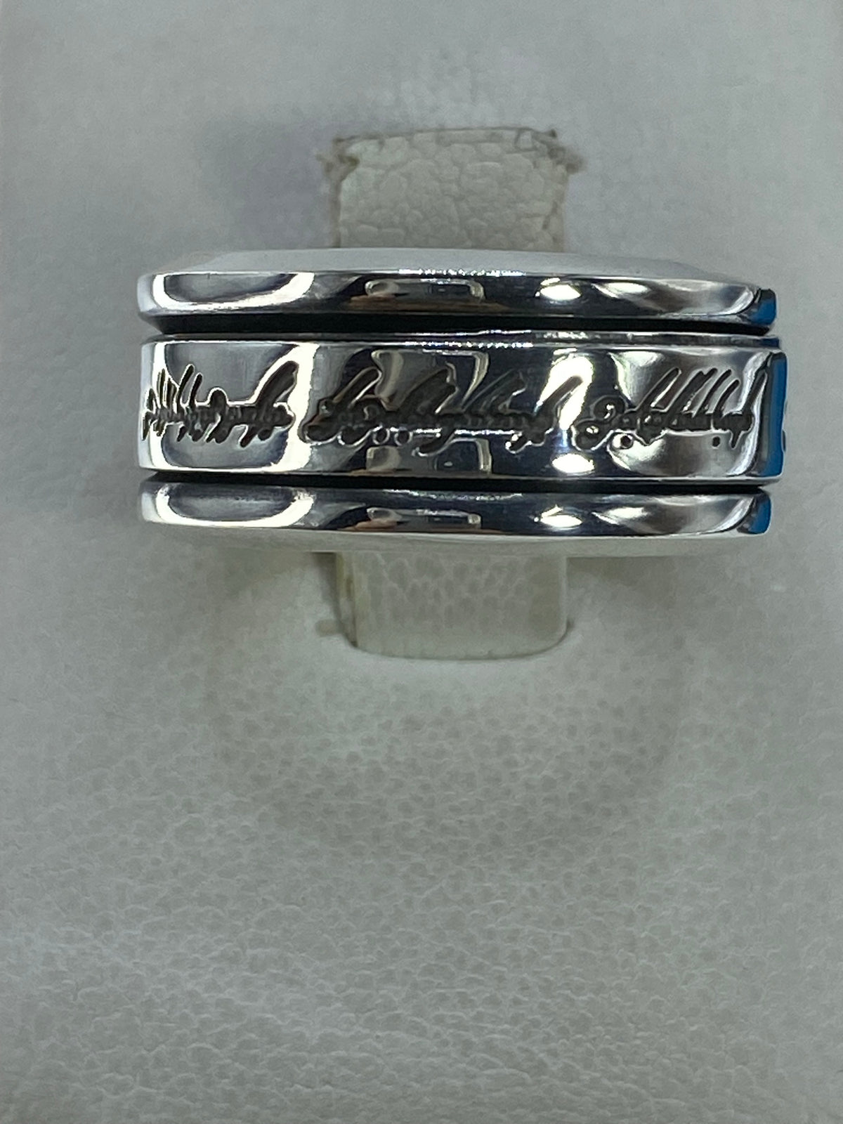 Anillo de plata 925 con banda ancha e inscripción grabada, visto desde arriba sobre fondo blanco