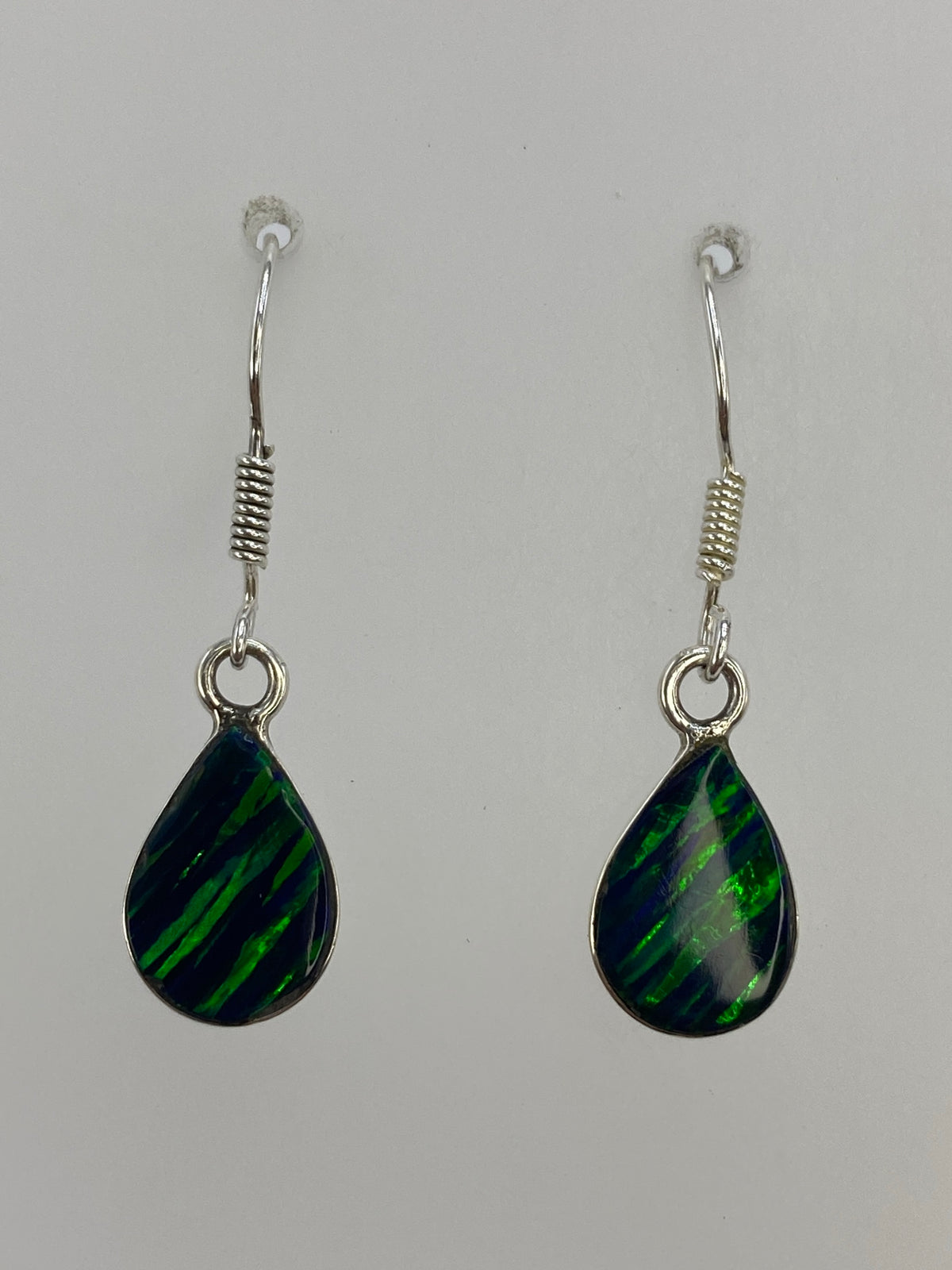 Aretes de plata 925 con ópalo de fuego verde engastado, mostrando el brillo de la piedra natural