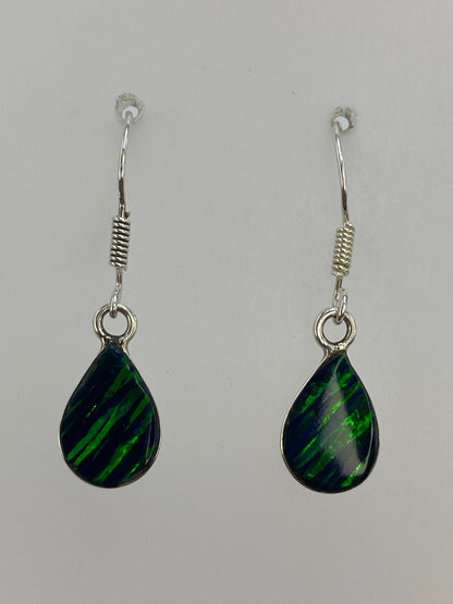 Aretes de plata 925 con ópalo de fuego verde engastado, mostrando el brillo de la piedra natural