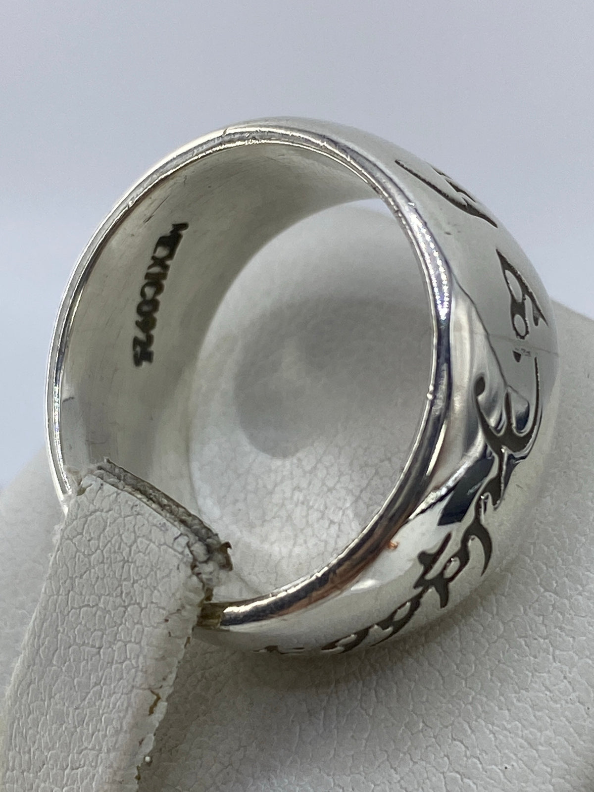 Anillo en el dedo, luciendo el acabado espejo pulido y el grabado