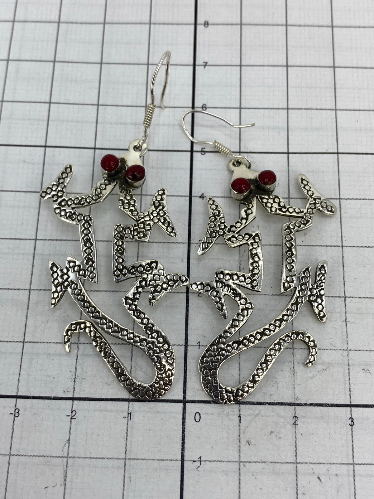 Par de aretes de plata con coral rojo sobre escala de centímetros