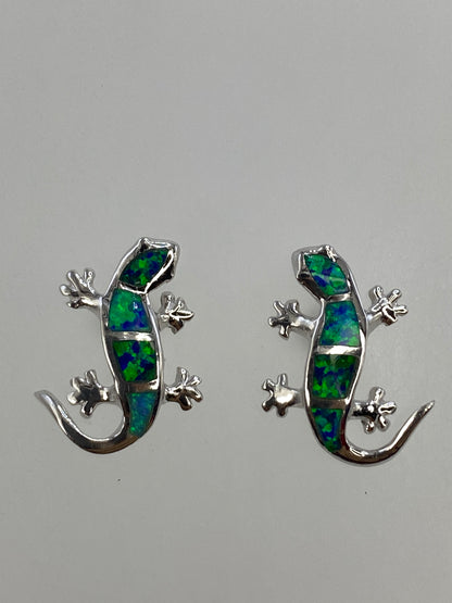 Aretes de lagartija sobre regla mostrando tamaño exacto de 1.7 × 1.4 cm