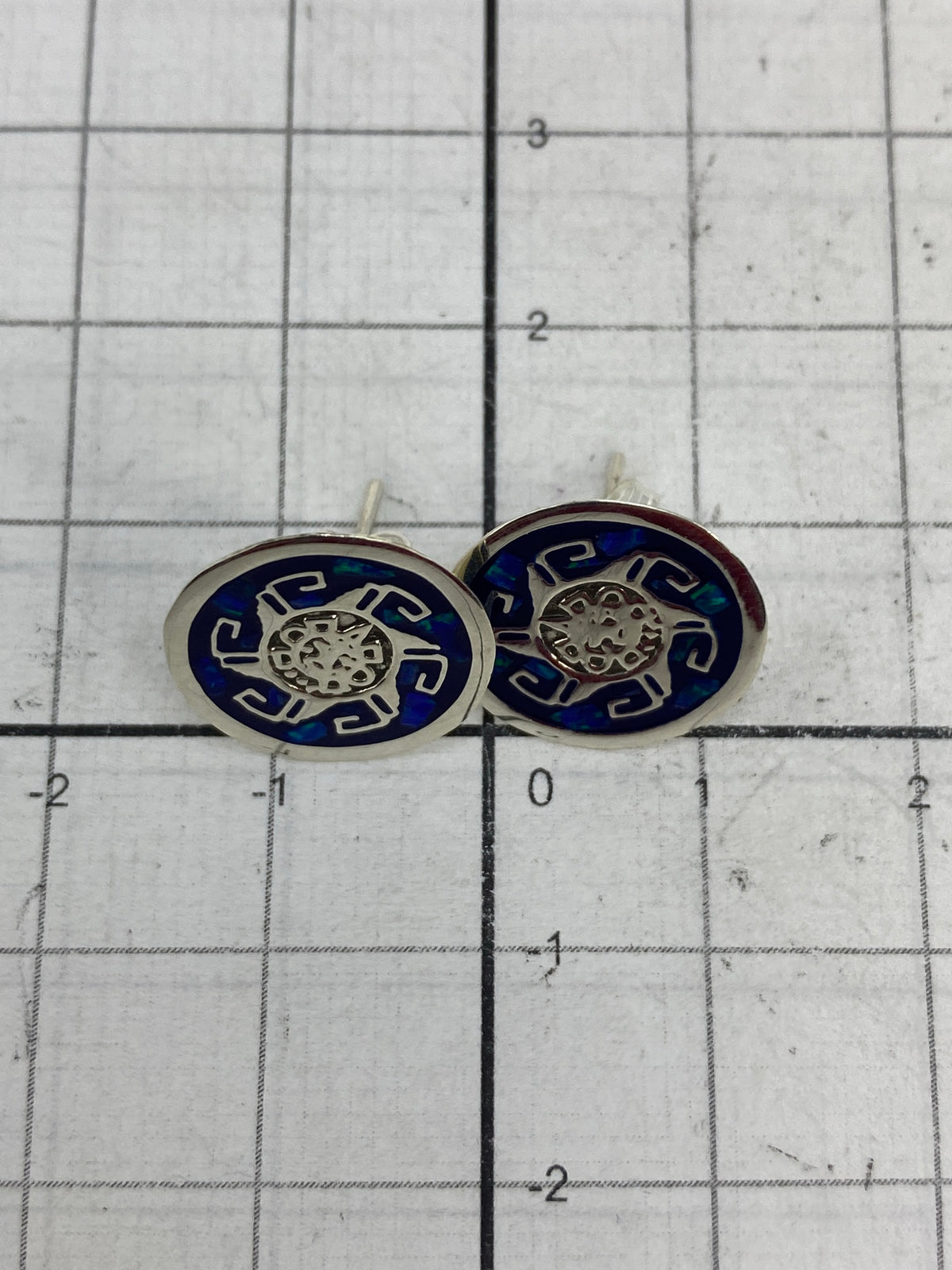Aretes pesados en balanza de precisión, mostrando 1.06 gramos