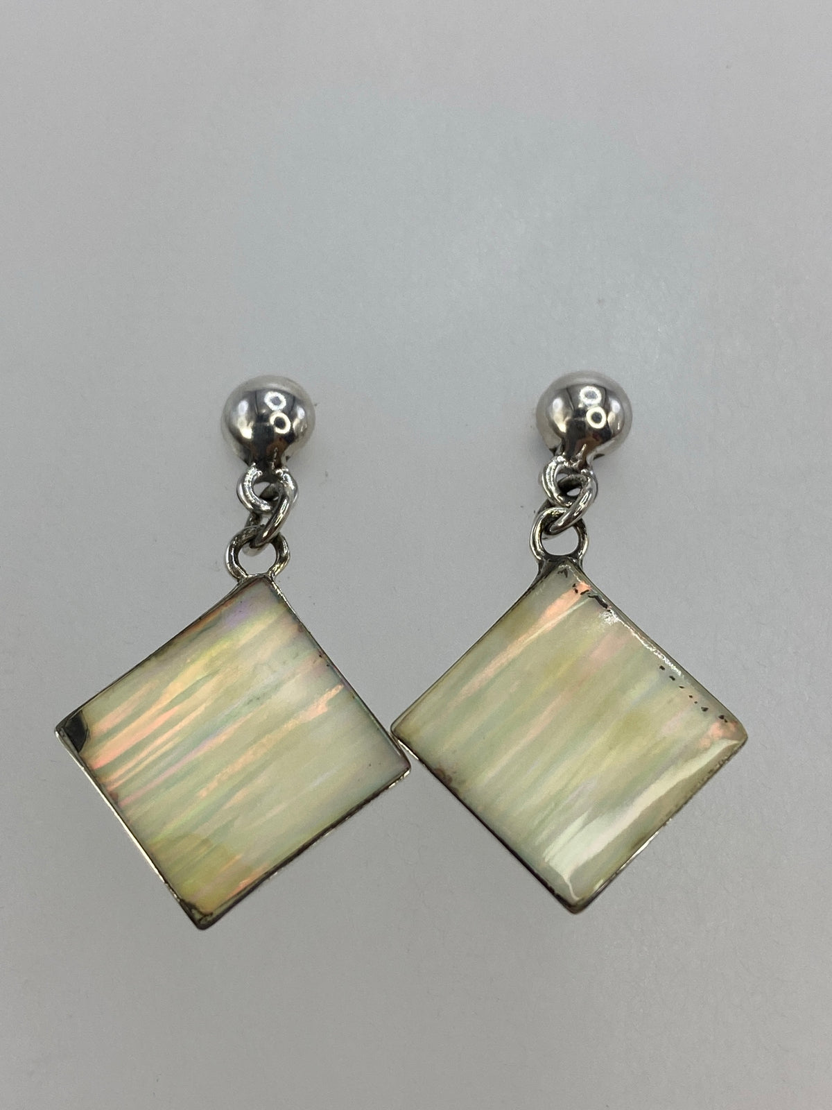 Detalle de la incrustación a mano de madre perla blanca en plata 925, mostrando brillo iridiscente