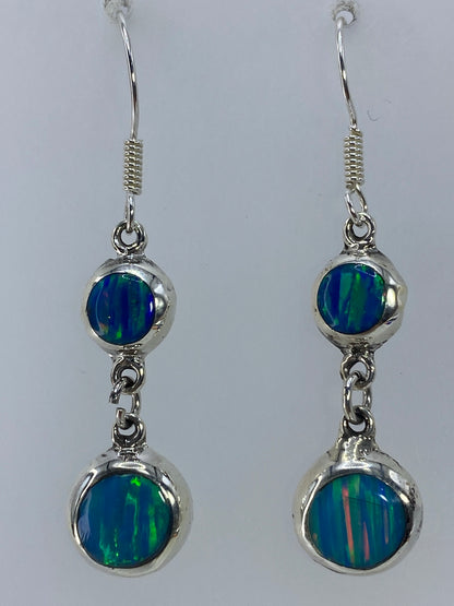 Par de aretes de plata 925 con ópalo de fuego verde olivo, colgando sobre fondo blanco